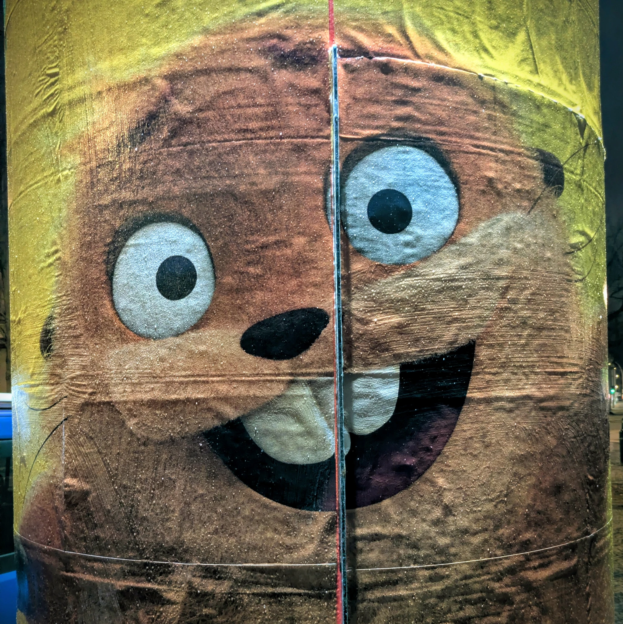 ein gezeichnetes fellmonster mit irrem blick auf einem plakat auf einer Litfaßsäule 