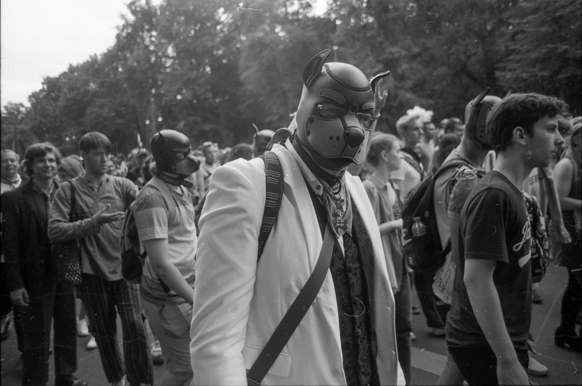 black and white photo of group of people some wear a dog mask 