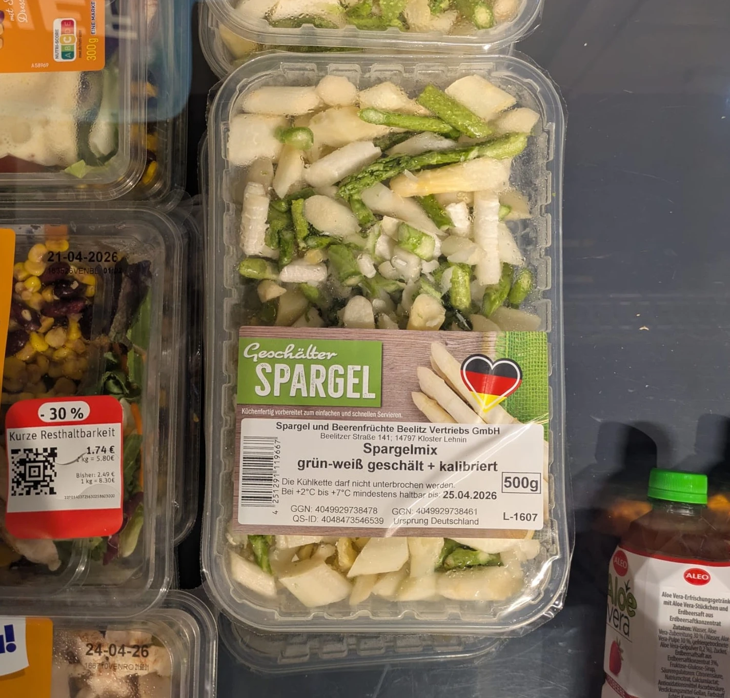 zwischen verschiedenen Produkten eine schale Spargel mit der Aufschrift 

Geschälter Spargel
Spargelmix grün-weiß geschält und kalibriert