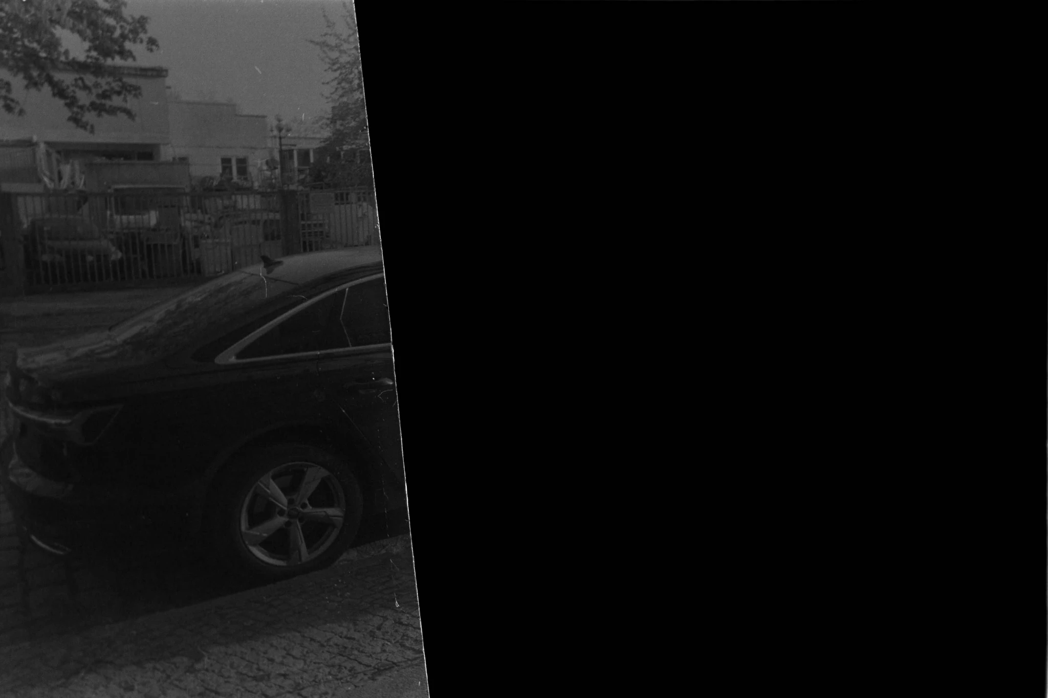 black and white image of a car but only the back of the car is visible and the rest is black