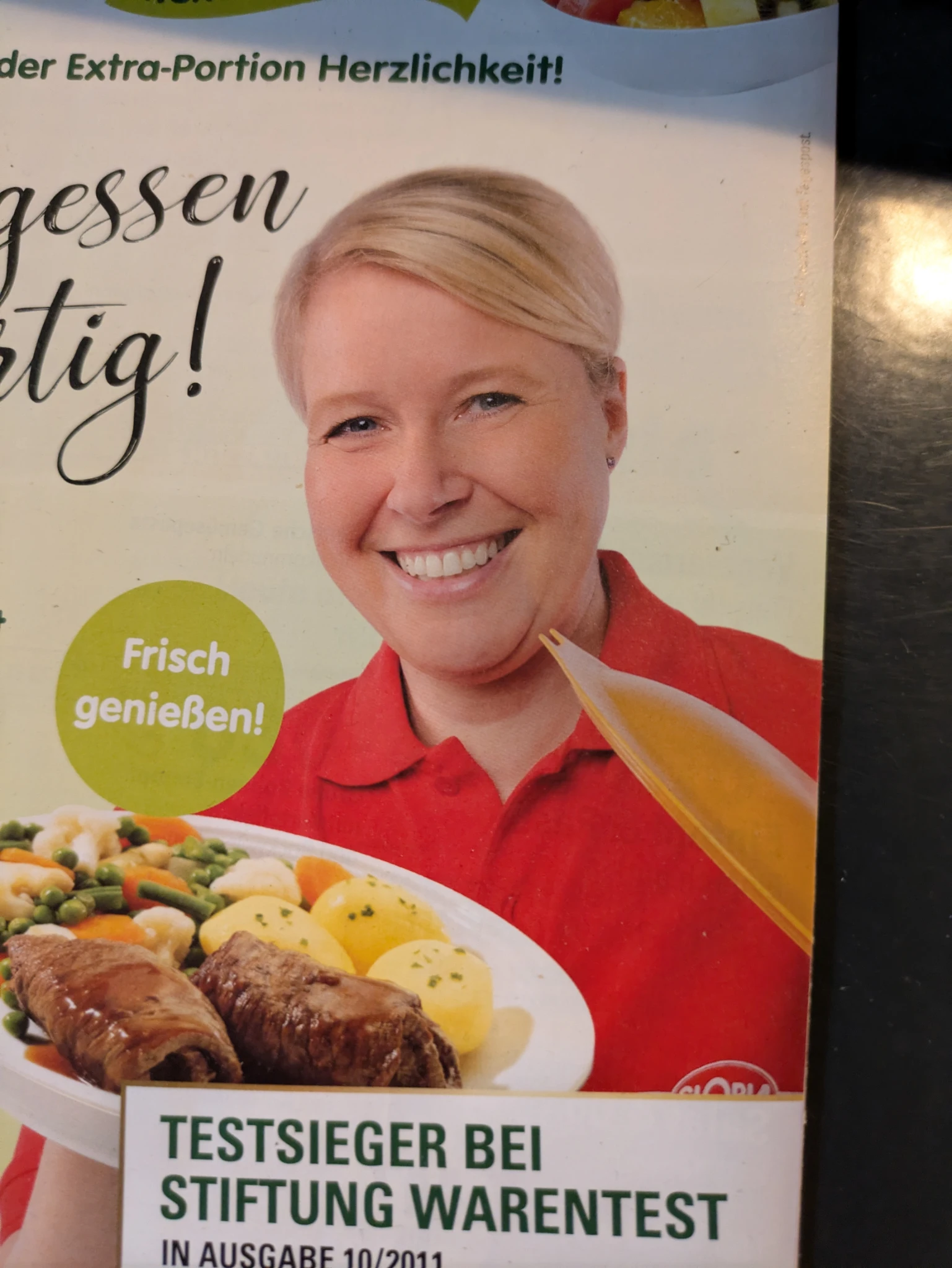 eine lächelnde frau auf einem werbeflyer hält einen teller mit essen in die kamera. drumherum ist schrift

frisch genießen
testsieger bei Stiftung warentest
extra portion herzlichkeit