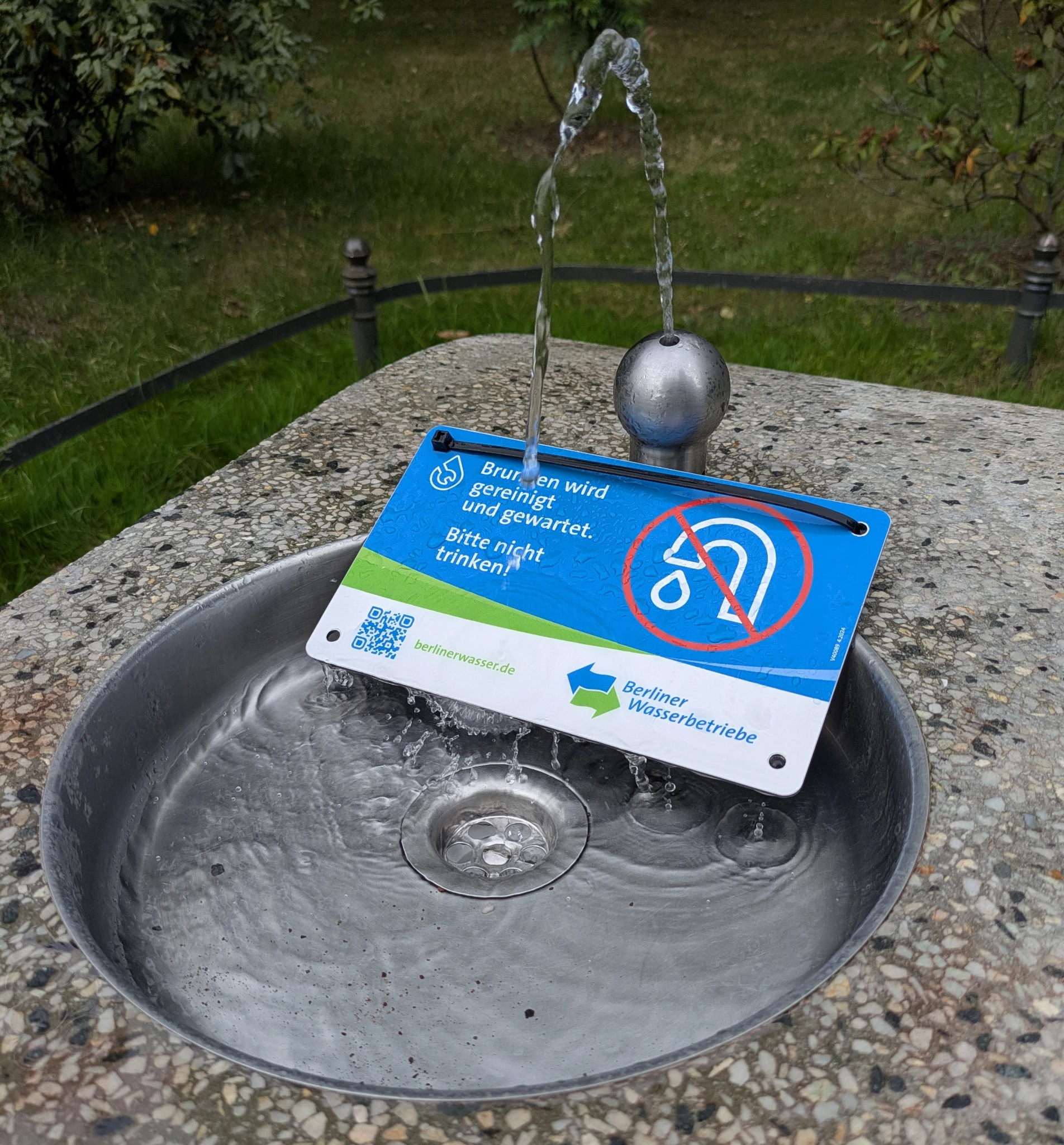 ein trinkbrunnen im park, aus dem wasser strömt, daran ein schild

KEIN TRINKWASSER
