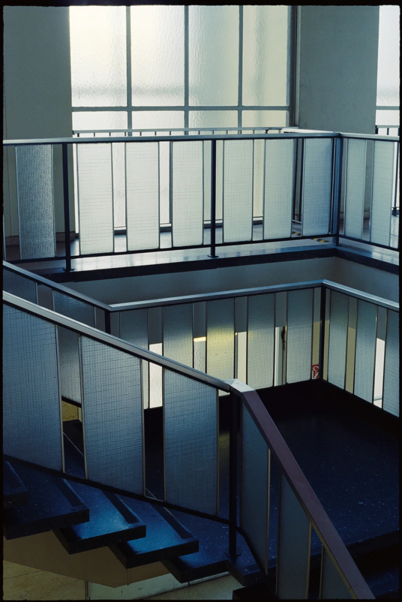 ein treppenhaus, die großen fenster illuminieren die treppen, alles ist in kaltem blau getaucht