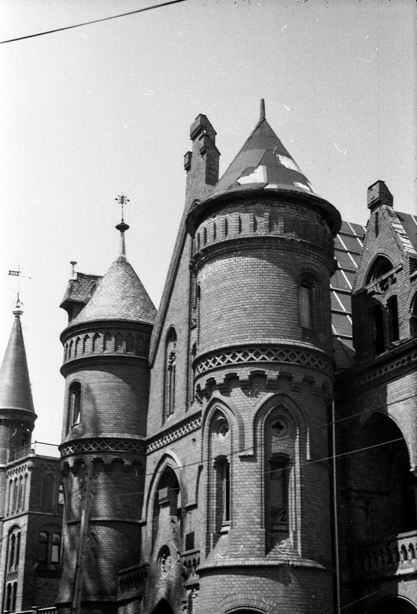 schwarzweiße detailansicht eines gebäudes im historisierenden stil. zahlreiche türme, zinnen und die fenster erinneren an eine burg.