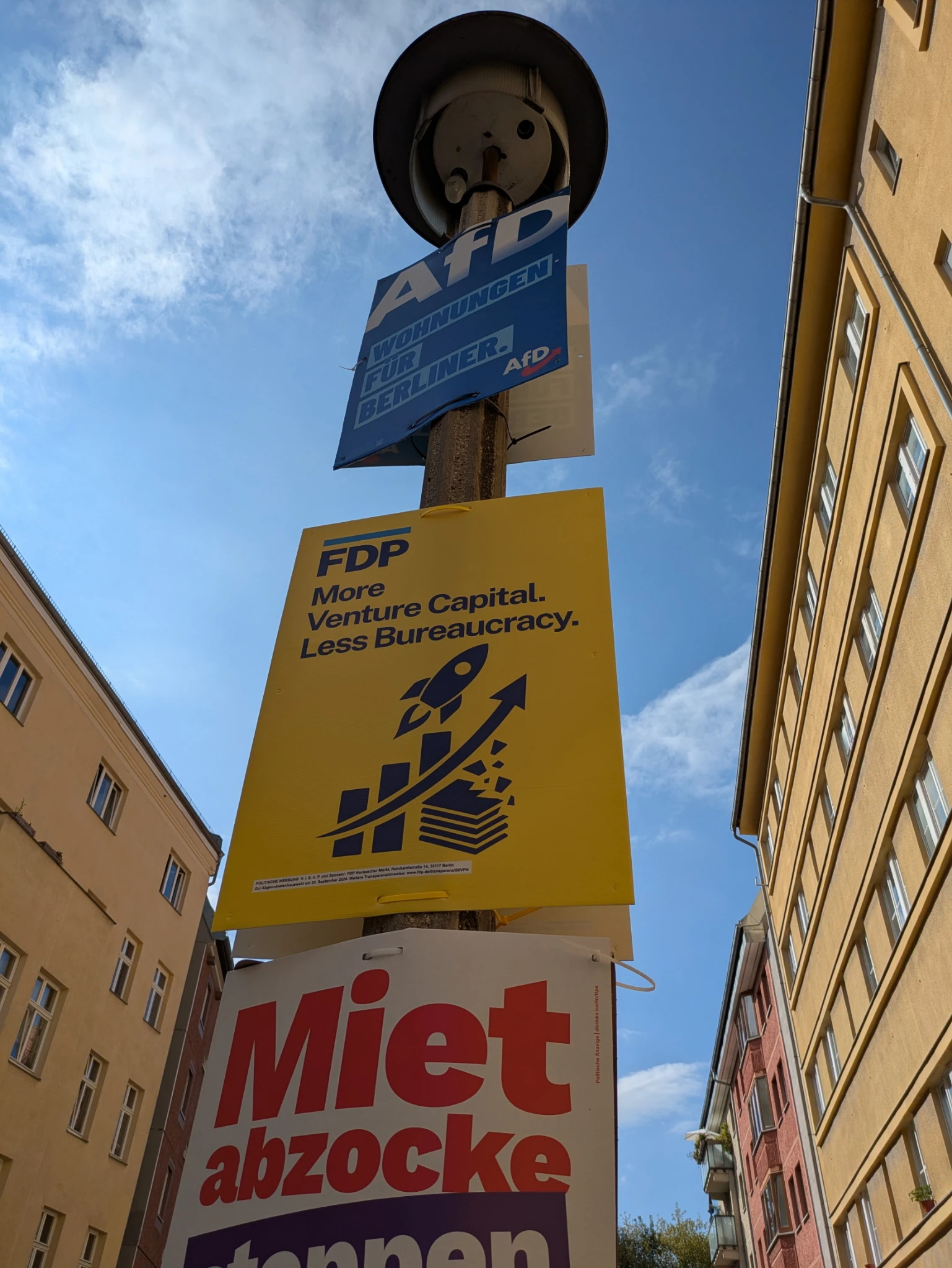 laternenpfahl mit drei plakaten zwischen afd und linke wirbt eine spaßpartei "F.D.P." mit "More venture capital less bureaucracy" und einer rakete