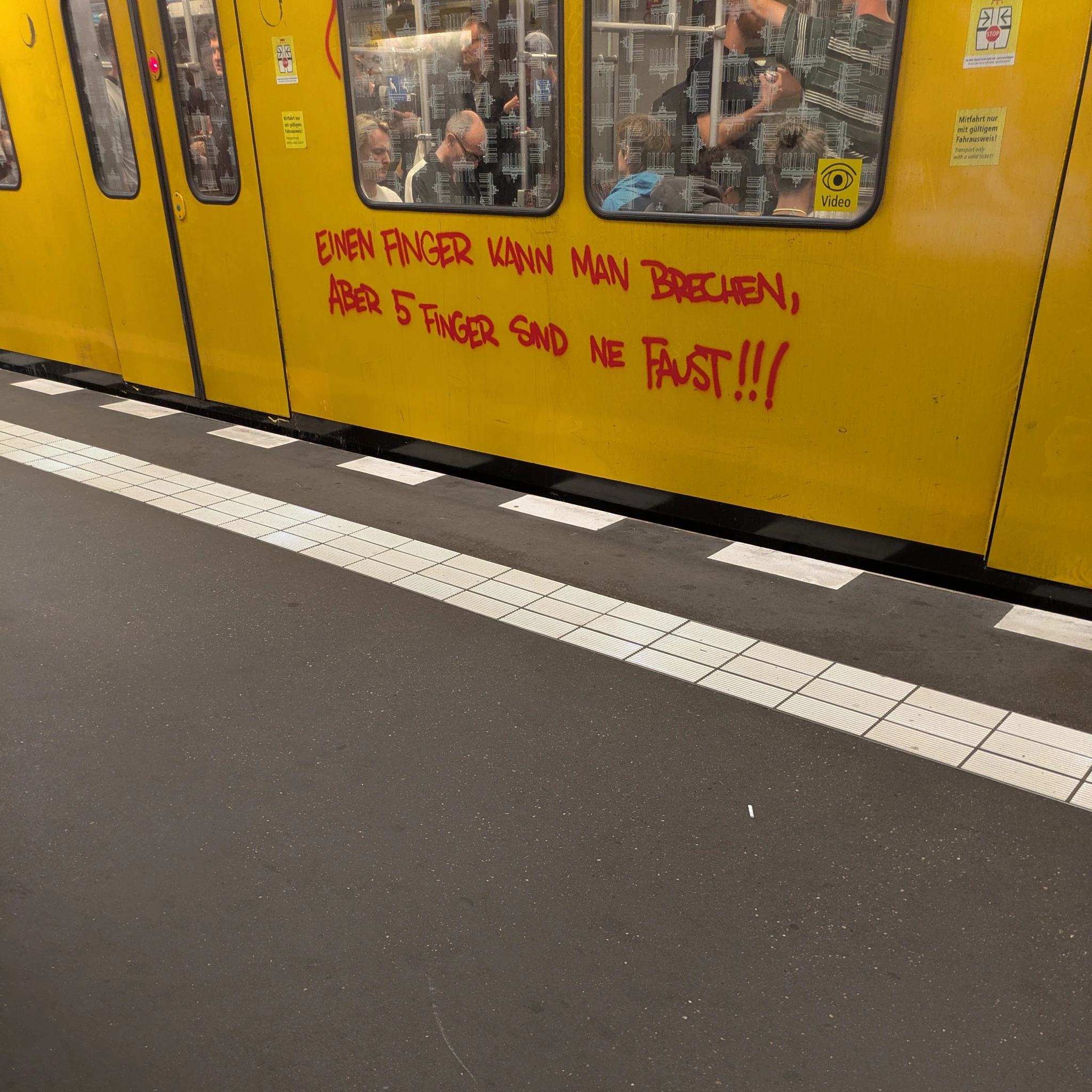 ein stück gelbe ubahn auf dem bahnsteig, in rot hat jemand drauf geschrieben 

einen finger kann man brechen
aber 5 finger sind ne faust!!!