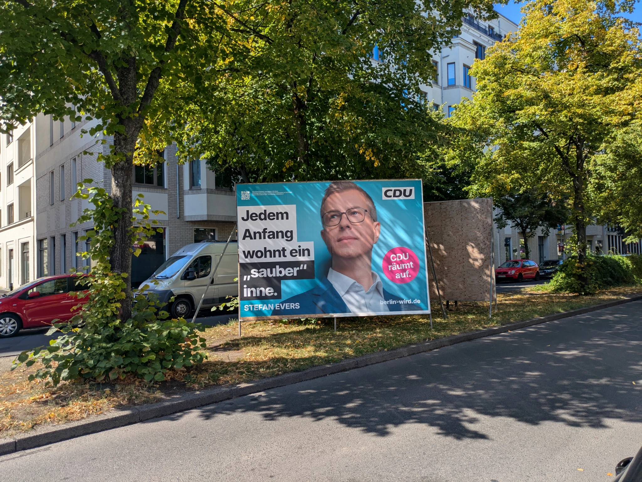 ein wahlplakat in hellblau, ein mittelalter weißer mann guckt in die luft, wir sehen nur kopf und schulter. darauf steht 

Jedem Anfang wohnt ein "sauber" inne.

das plakat steht auf einem grünstreifen auf einer straße.