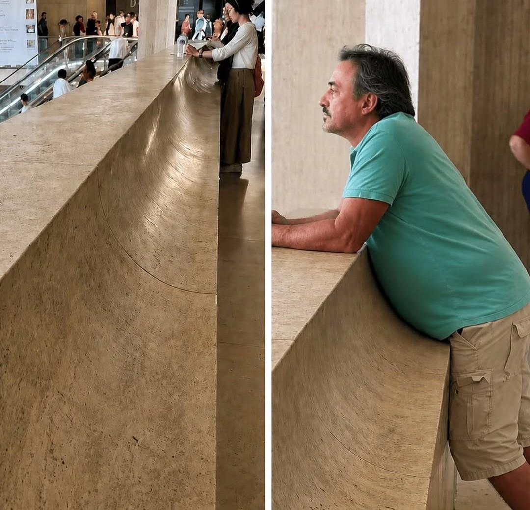 dans le hall d'un bâtiment public, la courbure d'un parapet (garde-corps) épouse à la perfection celle du ventre à bière d'un homme appuyé dessus