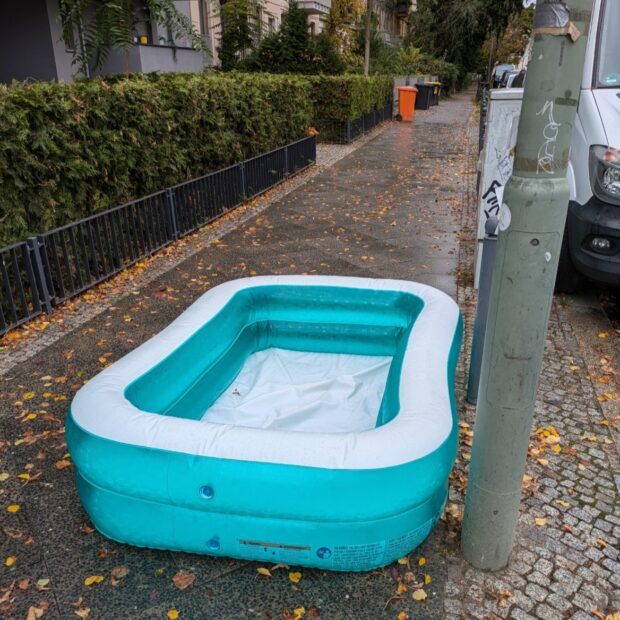 ein kleiner aufblasbarer pool steht auf einem herbstlichen bürgersteig.