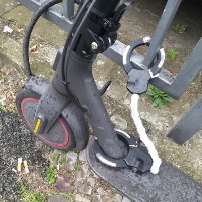 detail: electric scooter secured at a fence with handcuffs